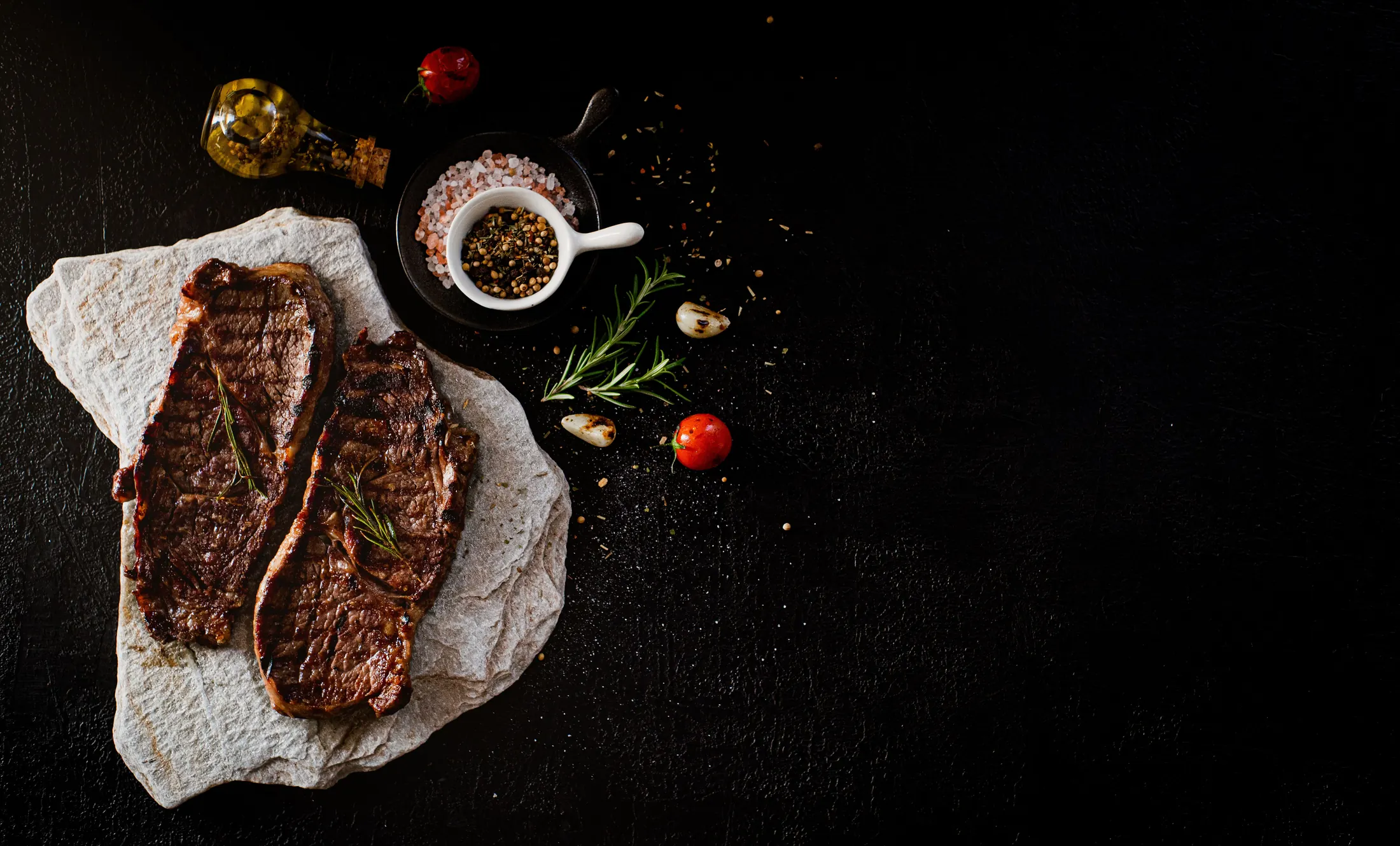 Pièces de viande grillées, herbes et épices sur un fond sombre