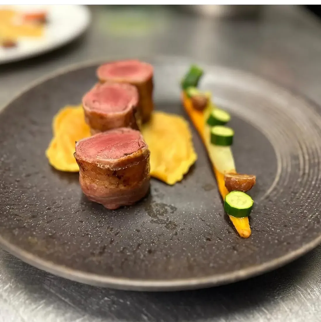 Plat du chef dressé avec une viande rosée et des légumes de saison